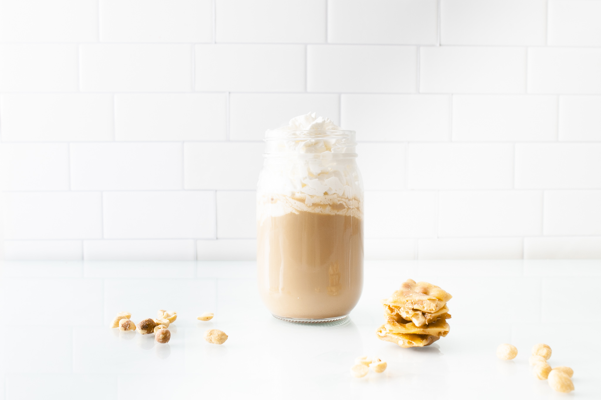 peanut brittle with hot latte and peanuts scattered